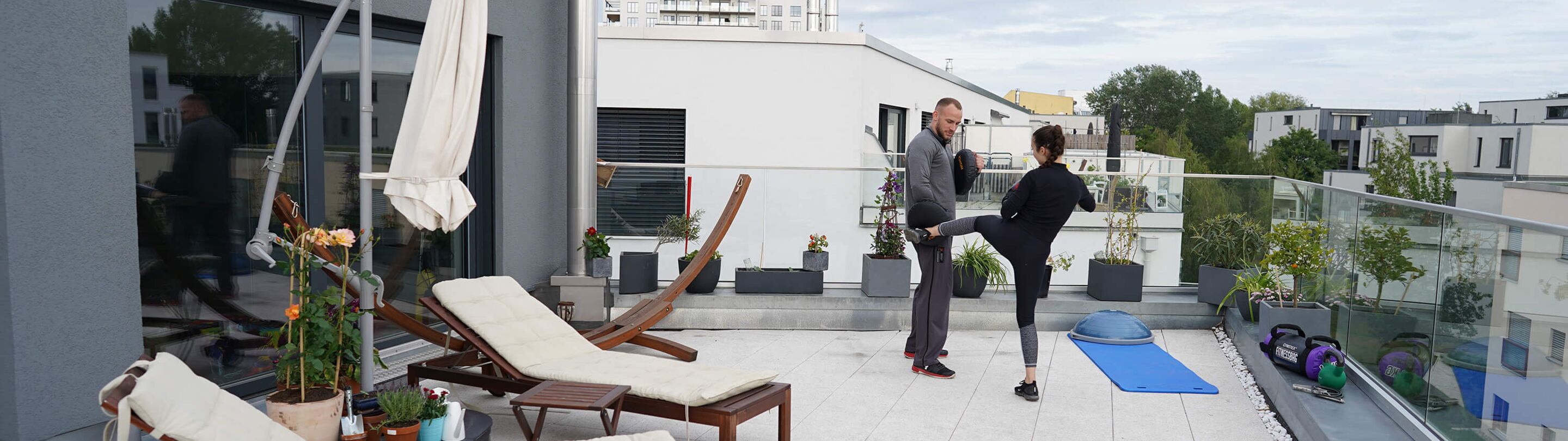 Fitnessboxen zu Hause auf der Terrasse: Trainer und Klientin im Freien.