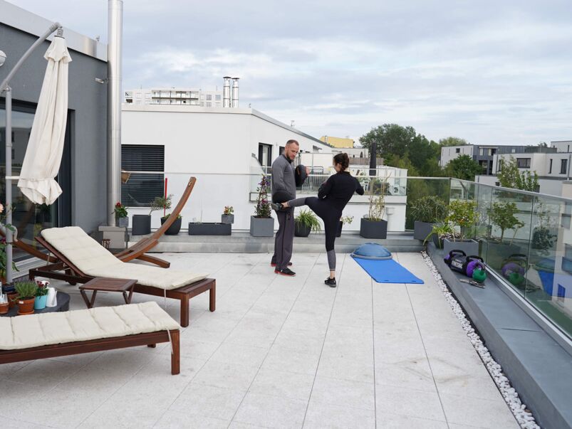 Fitnessboxen zu Hause auf der Terrasse: Trainer und Klientin im Freien.